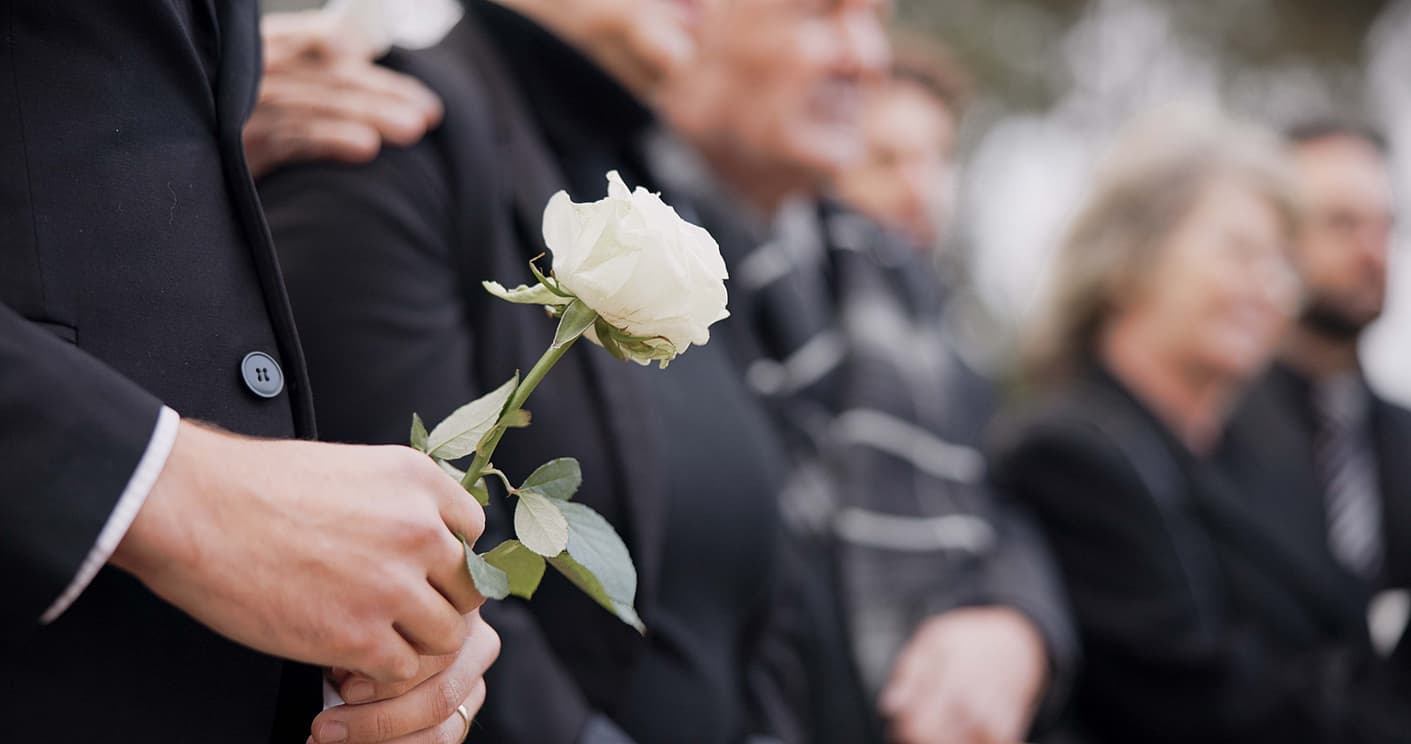 A family gathered in remembrance, holding a white rose