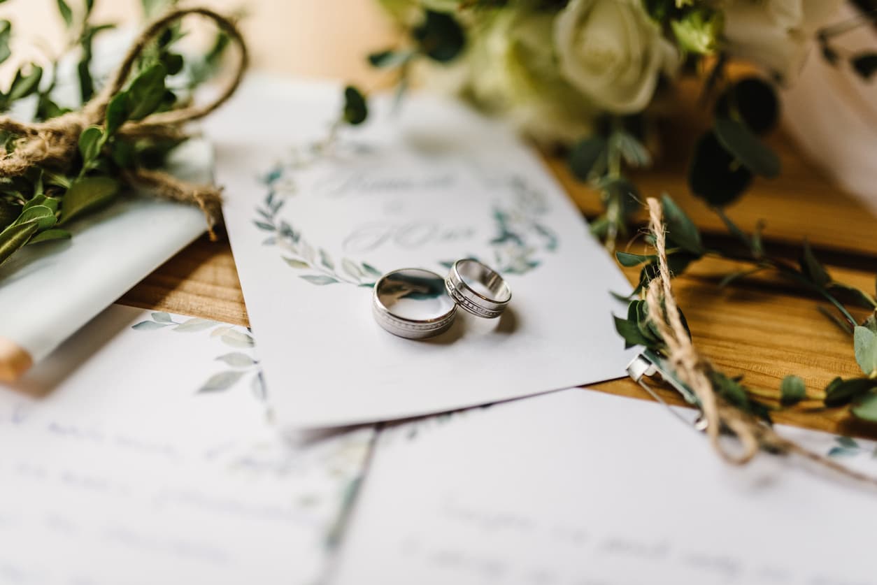Wedding rings resting on a botanical ceremony invitation