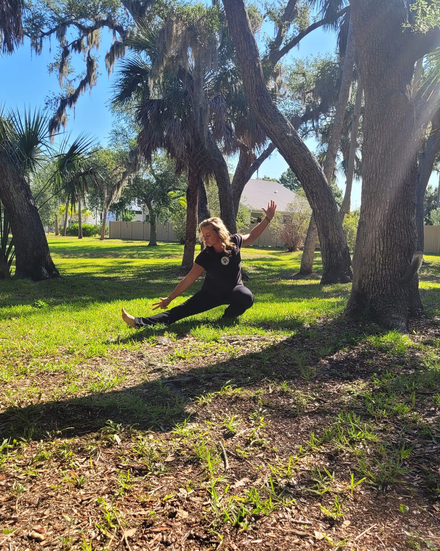 Dr. Jessica Lipham practicing Qi Gong outdoors beneath oak trees