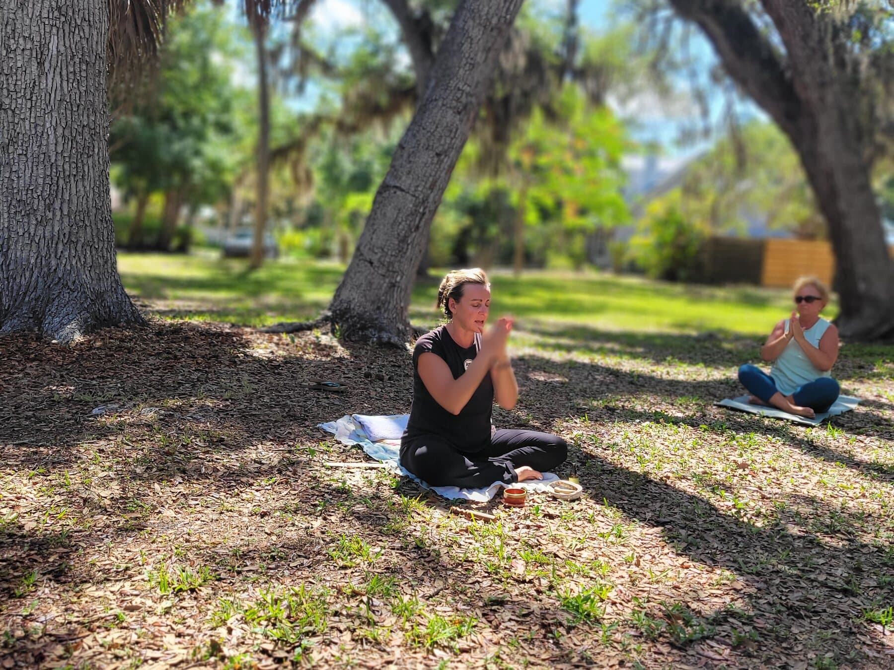 Dr. Lipham leading seated Qi Gong meditation outdoors with a student nearby